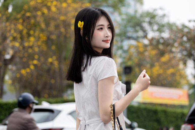 Outdoor portrait of a young woman in Hanoi, Vietnam, wearing a flower in her hair.